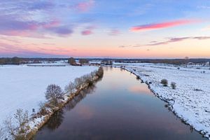 Vecht river flowing through a snowy winter landscape during sunset