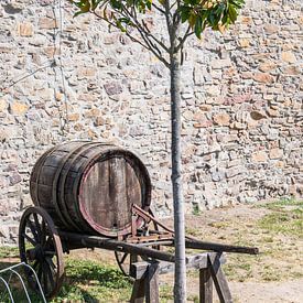 Vieille brouette avec un tonneau de vin contre le mur d'un domaine viticole sur Wim Stolwerk