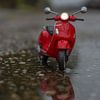 Miniatuur Vespa scooter in de regen en reflectie van John van de Gazelle