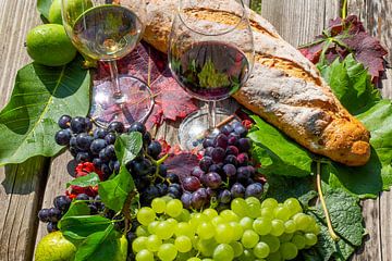 Ripe grapes decorated with wine glasses on a wooden table by Udo Herrmann