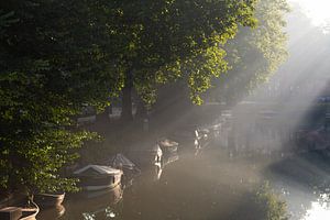 Le soleil perce et brille sur les bateaux dans les canaux d'Utrecht