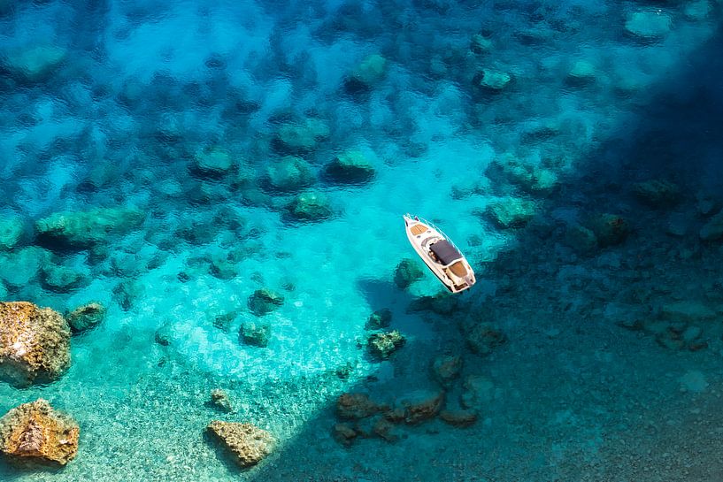 Boat in crystal clear blue waters in Greece by Laura Wubben