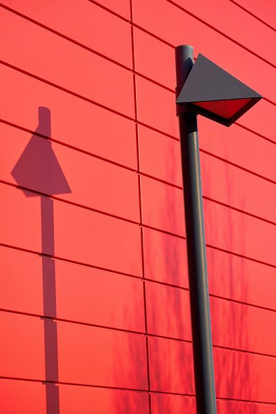 Lantern in front of the red facade of a house by Heiko Kueverling