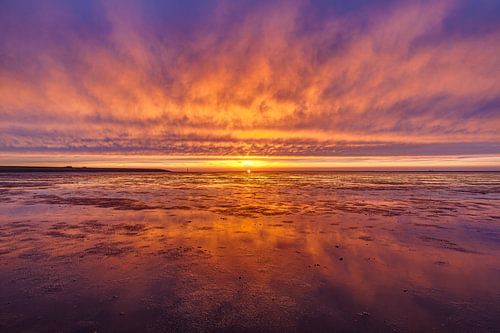 Vurige zonsondergang boven het wad