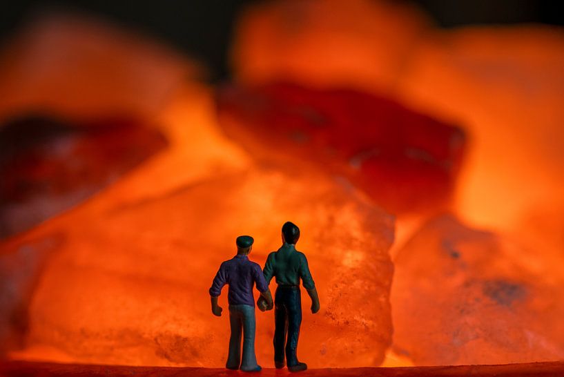 Männer zusammen Hand in Hand mit Blick auf die orange Feuer in Steinen von Jolanda de Jong-Jansen