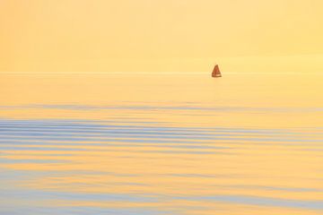 Een zeilschip op het IJsselmeer tijdens zonsondergang