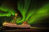 Noorderlicht in de nacht op IJsland met een schitterend lichtspel in de lucht en een oud vissersschi van Bas Meelker thumbnail