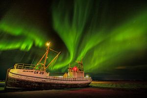 Nordlicht bei Nacht in Island mit einem schönen Lichtspiel am Himmel und einem alten Fischerboot im 