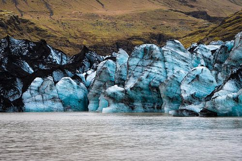 Blauw ijs tegen het ruige landschap van IJsland