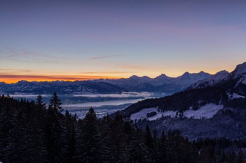 Sicht auf die bekannten verschneiten Berge Schreckhorn, Eiger und Thunersee im Winter bei Sonnenaufgang