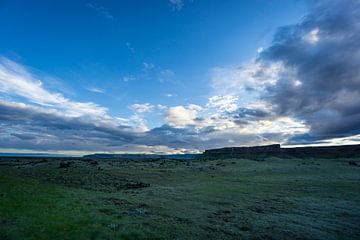 IJsland - Rotsachtig landschap en weidse groene velden met wolken bij zonsopgang van adventure-photos