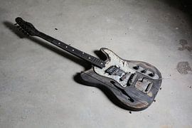 old burnt guitar on the floor of a ruin by Heiko Kueverling