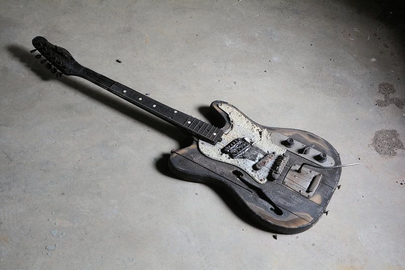 oude verbrande gitaar op de vloer van een ruïne van Heiko Kueverling