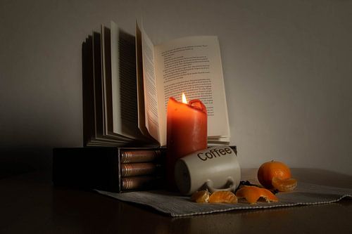 Still life of a coffee moment with books, tangerines and a candle