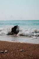 De l'eau de mer éclabousse un rocher sur la plage du Péloponnèse