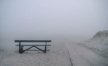 Leaving bench in the fog on the beach of Ameland.