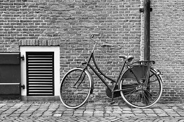 Traditionele zwarte fiets tegen een stenen muur