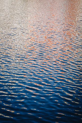 Reflectie van grachtenpanden op golven in het kanaal in Leiden, NL