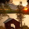 Altes Bootshaus mit Schaluppe auf dem schwedischen See bei Sonnenuntergang. von Maarten Visser