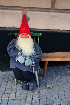 Gnome with a red pointed hat on a green wooden chair