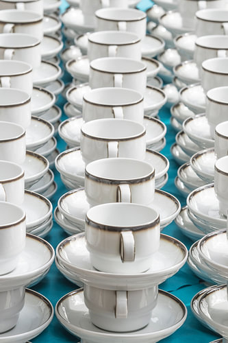 Witte koffiekopjes met bordstandaard op een rijtje gestapeld