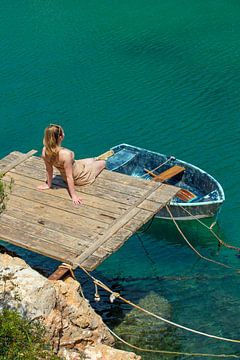 Jonge vrouw op een steiger met een vissersboot in Mallorca van t.ART