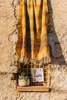 Traditioneller sardischer Stoff an einem rustikalen Fenster in Orotelli, Sardinien