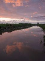 Reflectie van de zonsondergang en wandelaars