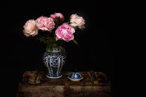 Delftsblauwe vaas met pioenen op een vintage kist