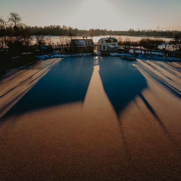 Schatig land huisjes in de zonsopkomst, schaduw valt op het ijs van Mike Helsloot