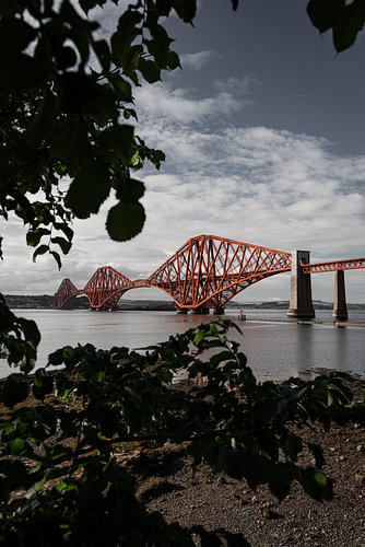 De rode brug in South-Queensferry met een kader van bladeren tijdens een wandeling