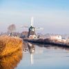 Hollandse molen in winters landschap aan het water van Inge van den Brande