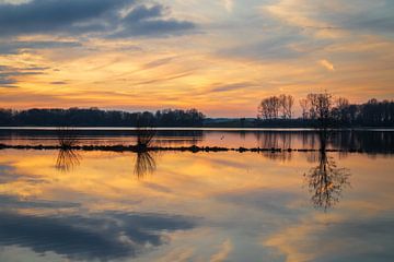 Le coucher de soleil coloré se reflète dans le lac de la zone de loisirs de Geestmerambacht. sur Bram Lubbers