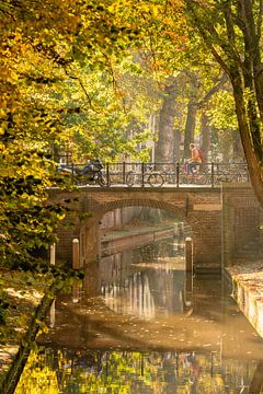 Fietser over brug niewe gracht in de herfst. van zeilstrafotografie.nl