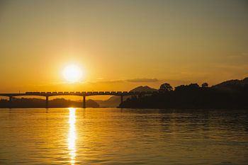 Zug auf Brücke bei Sonnenuntergang in Laos