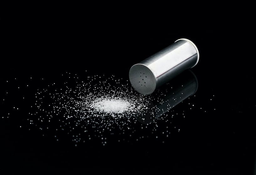 Salt shaker on a black background with grains of salt. by Nelemonsi Photo Art