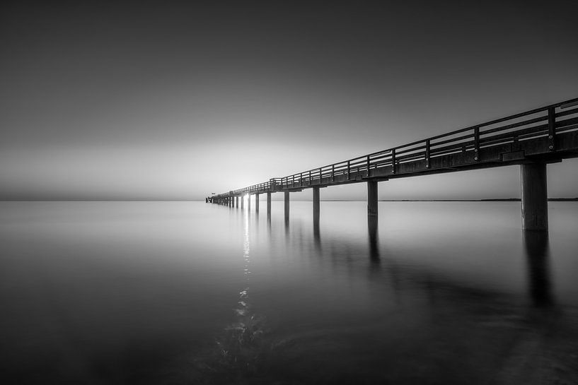 Sonnenaufgang an der Seebrücke von Boltenhagen in schwarzweiss. von Manfred Voss, Schwarz-weiss Fotografie