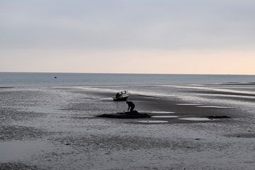 Silhouet van eenzaam figuur werkend in het zand bij laag water van Studio LE-gals