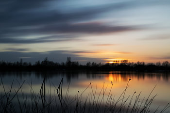 Zon ondergang aan een water kant.