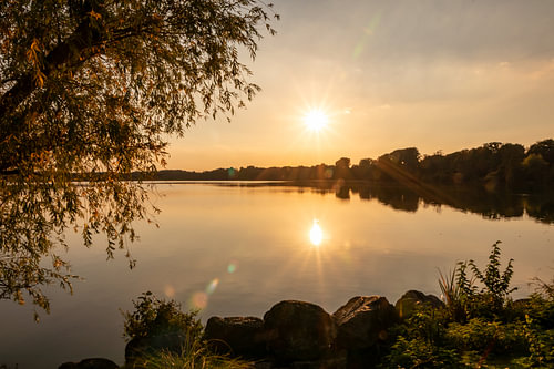 Romantische zonsondergang aan een idyllisch meer met zonneschijn en weerspiegeling