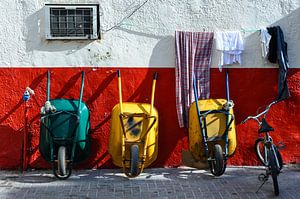 Vélo de pause et trois brouettes appuyés contre un mur.