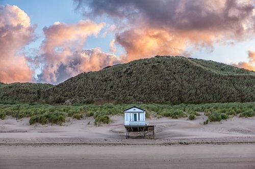 Strandhuisje op het strand bij opkomende zon aan de noorzeekust in Zeeland tegen een roze oranje bew