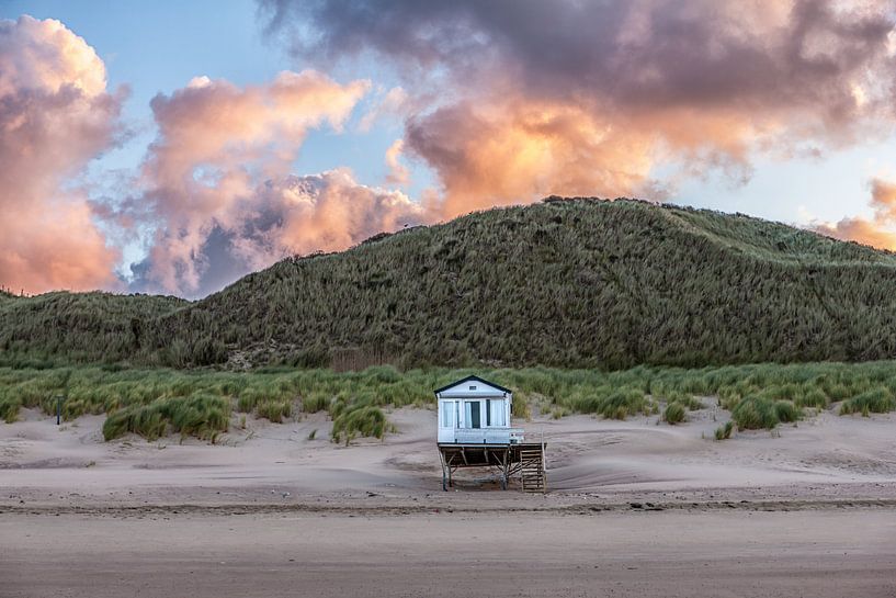 Strandhuisje op het strand bij opkomende zon aan de noorzeekust in Zeeland tegen een roze oranje bew van Wout Kok