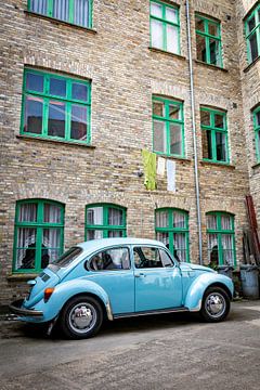 Retro blauwe klassieke auto geparkeerd naast bakstenen gebouw