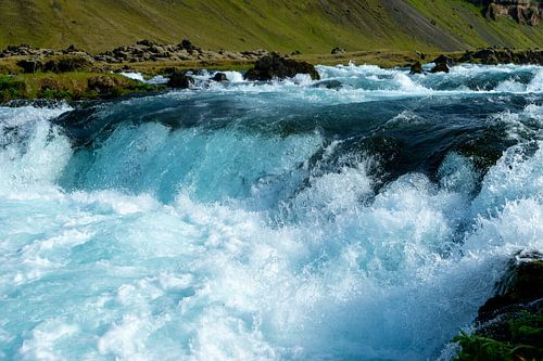Stromschnellen vor grün bewachsener Felswand