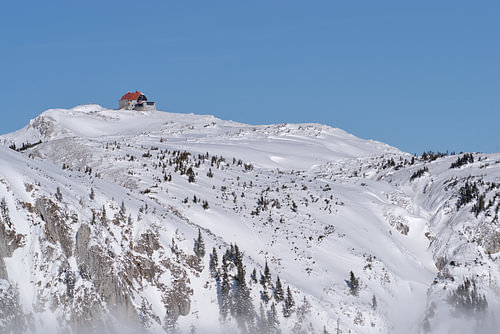 Refuge de montagne sur un sommet enneigé, sous un ciel dégagé