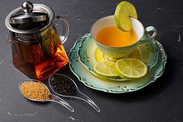 Schwarzer Tee mit Limette, arrangiert auf einem Platzset mit Früchten