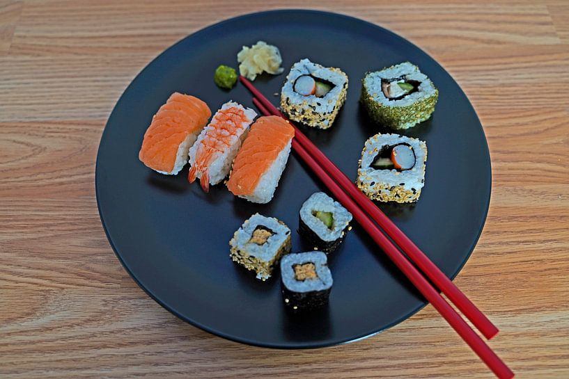 Sushi disposés sur une assiette avec des baguettes. par Babetts Bildergalerie