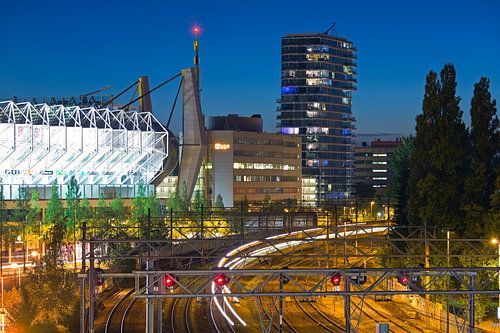Nachtaufnahme der Bahngleise, des PSV-Stadions und des Hartje New York-Gebäudes in Eindhoven