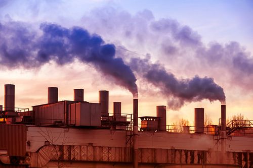 Cheminées fumantes d'une usine au coucher du soleil
